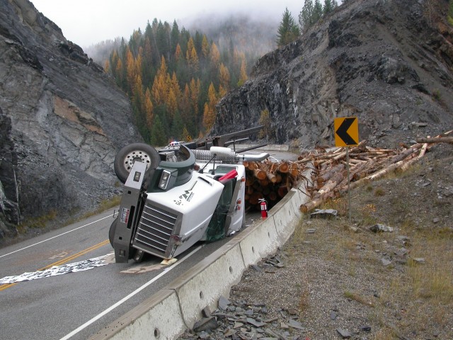 Logging truck rolls over on sharp curve
